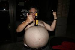 Ce monsieur fait tenir une bouteille de bière sur son gros ventre ferme et rebondi